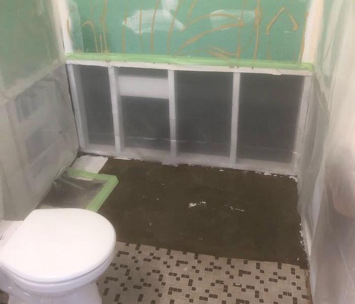 Bathroom with the tub and wall tiles removed with the area covered in plastic