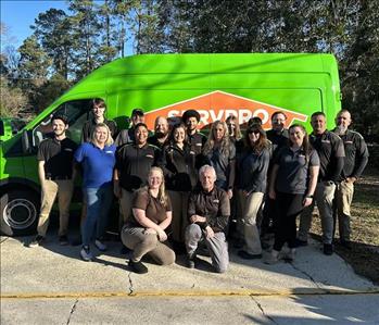 SERVPRO team, standing in front of a green SERVPRO Van