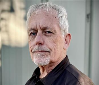 Joe Scott, Owner, in a black dress shirt standing in front of a white background.