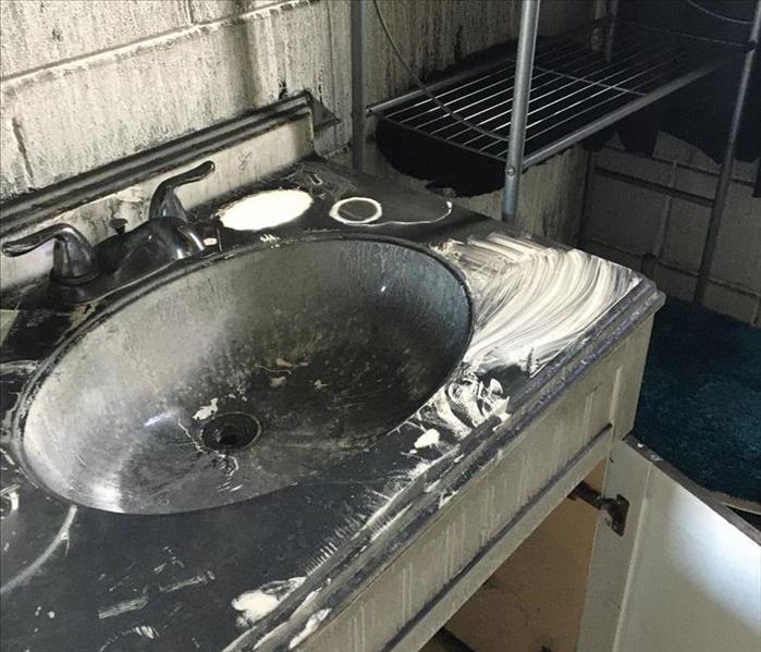 Sink and counter in bathroom with heavy smoke damage