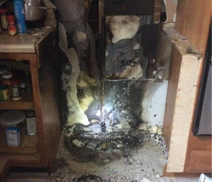 Kitchen with missing oven with visible fire damage in the space