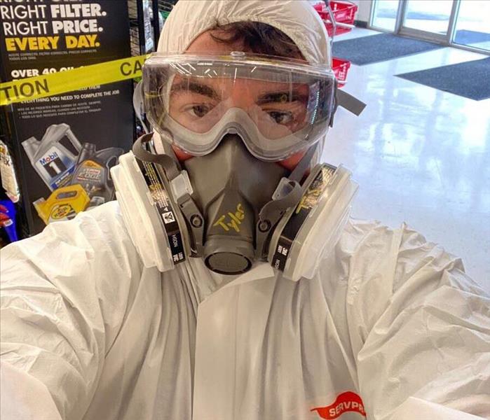 employee in face mask and googles wearing a white protective suit
