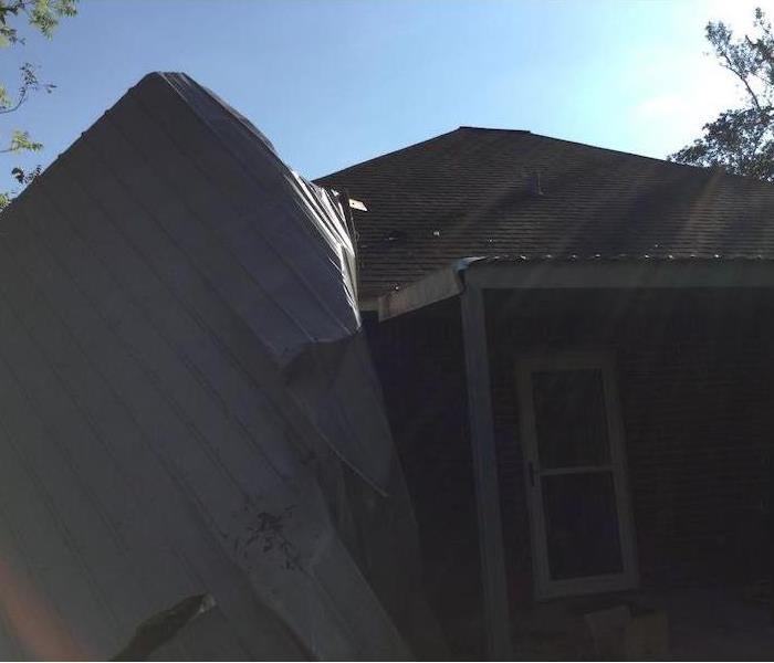 Tin roof blown on top of home roof