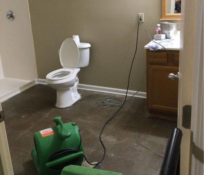 Bathroom with wet flooring and SERVPRO drying equipment