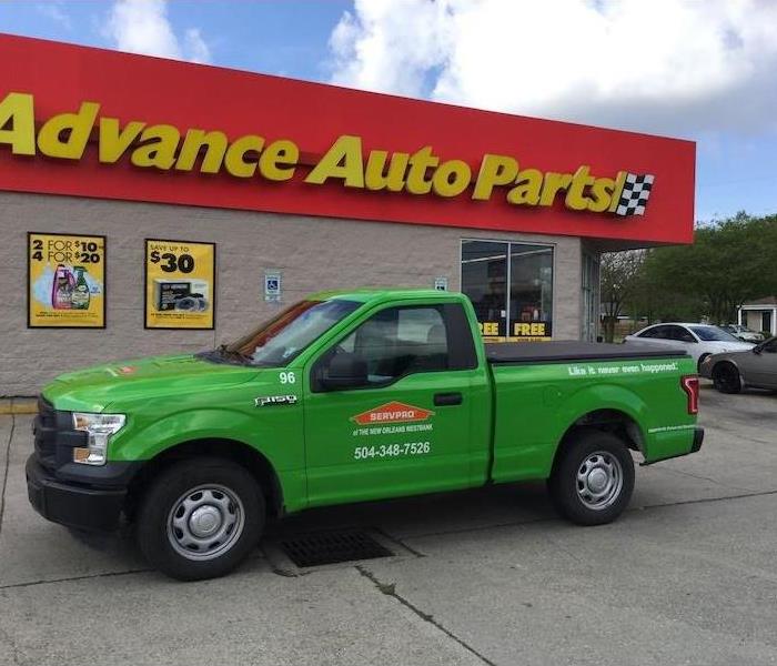 Green SERVPRO truck sitting in front of an auto part store