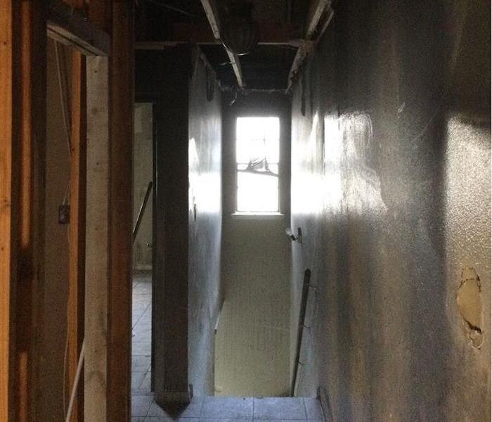 Fire damaged hallway in home with exposed framework